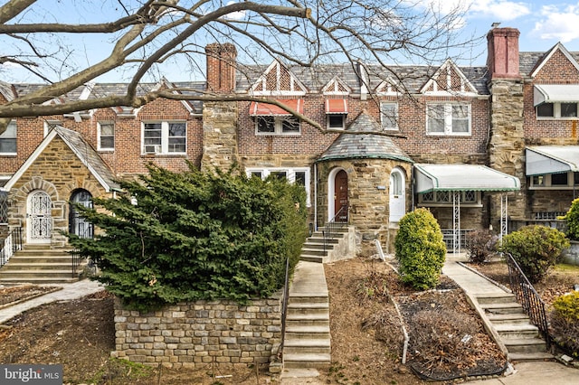 view of front facade with brick siding and a chimney