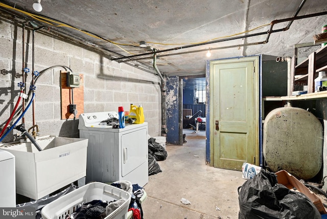 unfinished basement featuring washing machine and clothes dryer, a sink, and concrete block wall