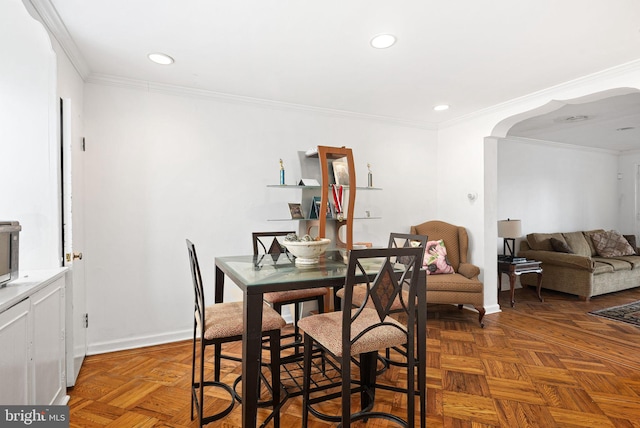 dining space with arched walkways, crown molding, baseboards, and recessed lighting