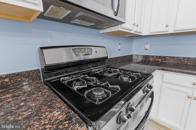 kitchen featuring stainless steel appliances, white cabinets, and dark stone countertops