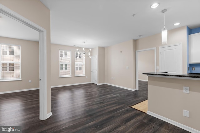 interior space featuring hanging light fixtures, dark wood-style floors, baseboards, and a chandelier