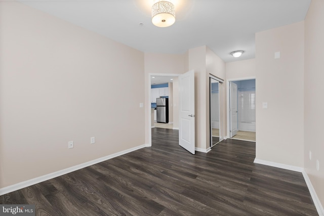 empty room with dark wood-style flooring and baseboards