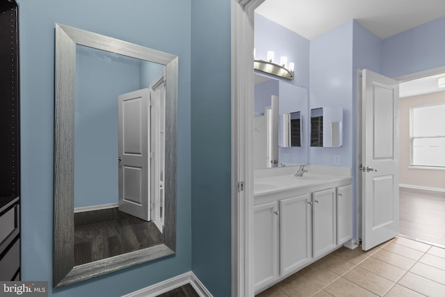 bathroom with double vanity, tile patterned flooring, baseboards, and a sink