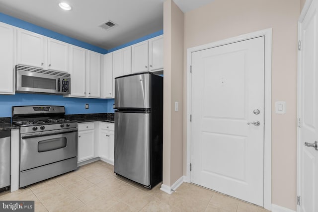 kitchen with light tile patterned floors, stainless steel appliances, visible vents, white cabinets, and dark stone countertops