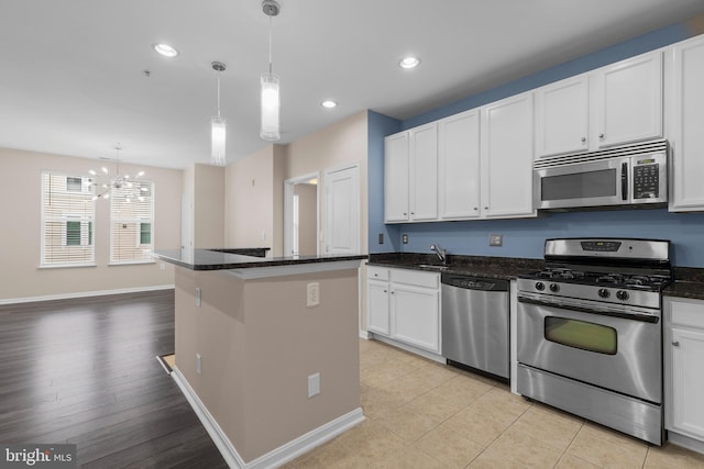 kitchen featuring recessed lighting, stainless steel appliances, a kitchen island, a sink, and white cabinets