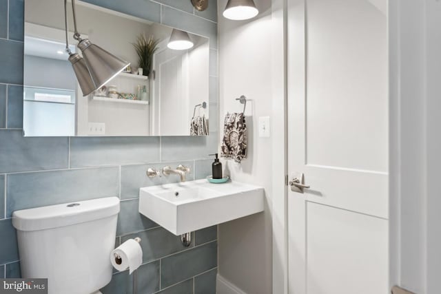 bathroom featuring a sink, tile walls, and toilet