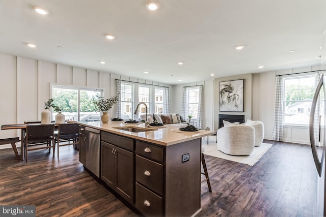 kitchen featuring stainless steel appliances, light countertops, open floor plan, a kitchen island with sink, and a sink