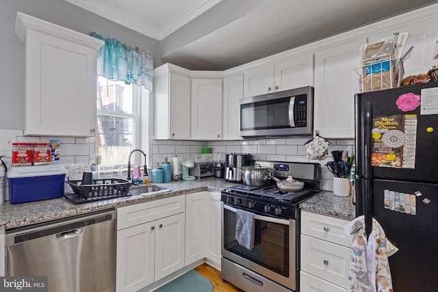 kitchen featuring appliances with stainless steel finishes, tasteful backsplash, a sink, and ornamental molding