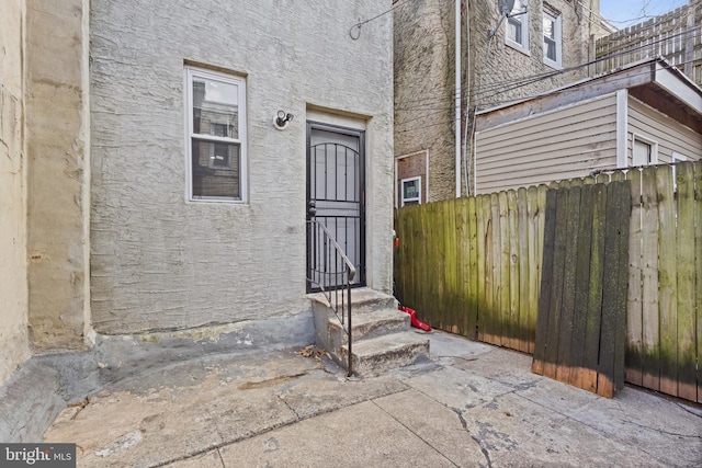 doorway to property with fence and stucco siding