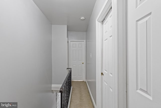 corridor with baseboards, an upstairs landing, and light colored carpet