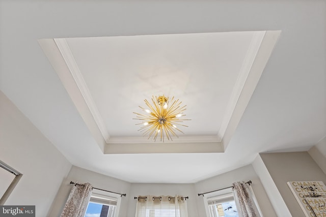 interior details featuring a raised ceiling, crown molding, and an inviting chandelier