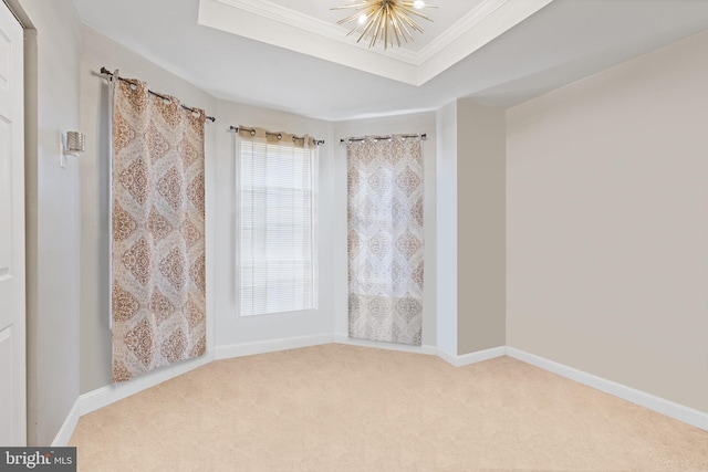 carpeted empty room with ornamental molding, a tray ceiling, baseboards, and an inviting chandelier