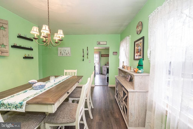 dining room with dark wood-style flooring, a notable chandelier, and baseboards