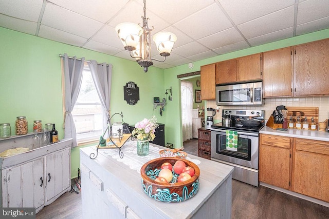 kitchen with dark wood-style floors, a drop ceiling, stainless steel appliances, and light countertops