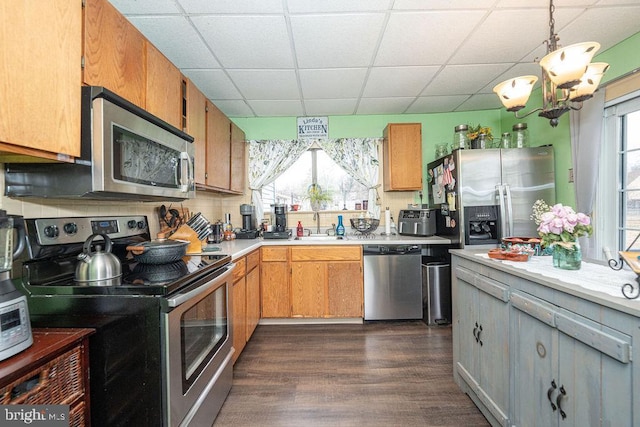 kitchen with a paneled ceiling, stainless steel appliances, dark wood-style flooring, a sink, and light countertops