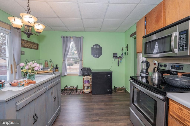 kitchen with stainless steel appliances, a drop ceiling, dark wood finished floors, and light countertops