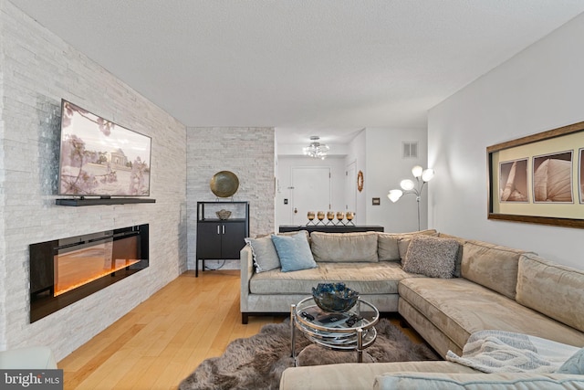 living room with a textured ceiling, a fireplace, wood finished floors, and visible vents