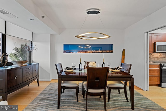 dining room with light wood-style floors, baseboards, and visible vents