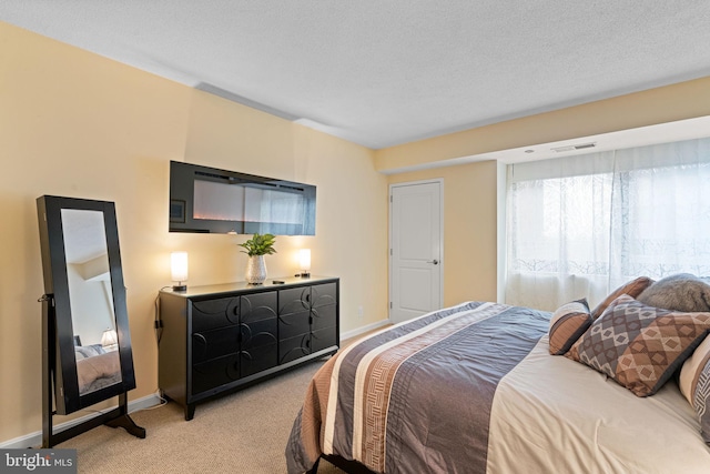 bedroom featuring light carpet, baseboards, visible vents, and a textured ceiling