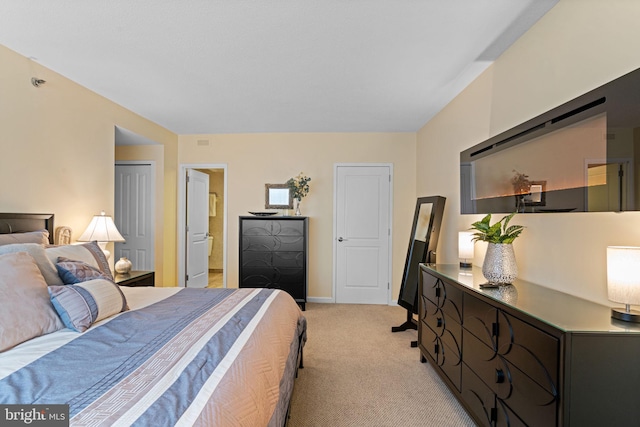 bedroom with light carpet, ensuite bath, and baseboards