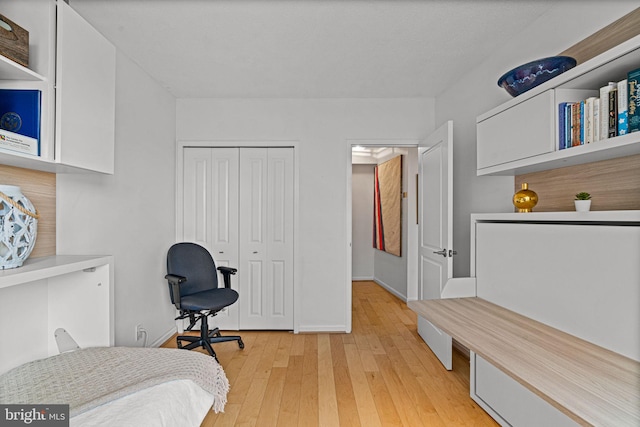 bedroom featuring light wood-type flooring, a closet, and baseboards