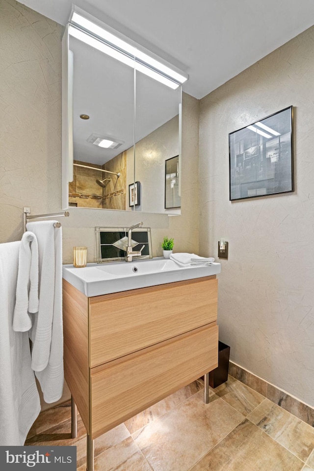 full bathroom with visible vents, a textured wall, vanity, and baseboards