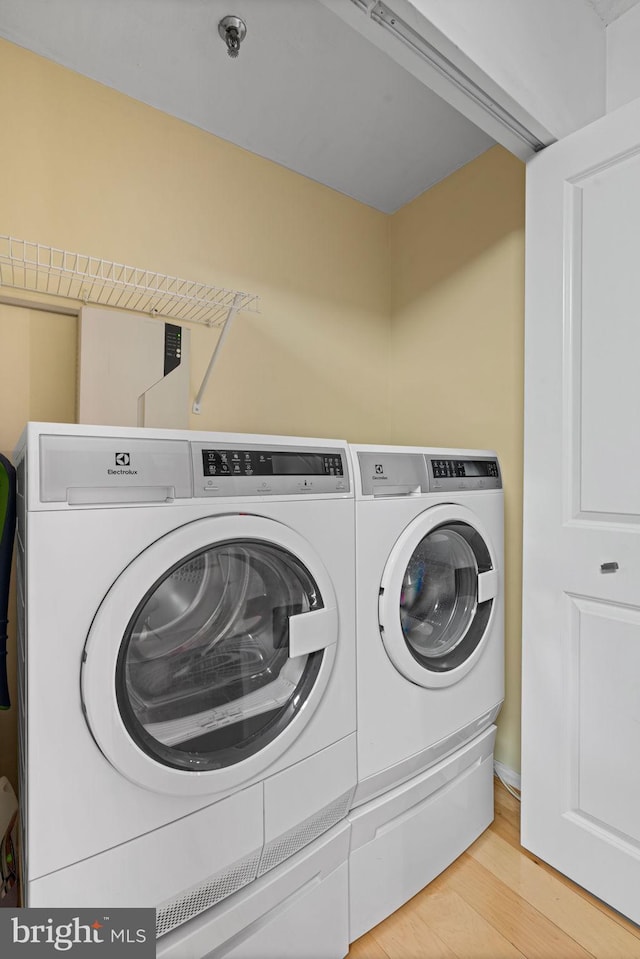 clothes washing area featuring laundry area, independent washer and dryer, and light wood-style flooring