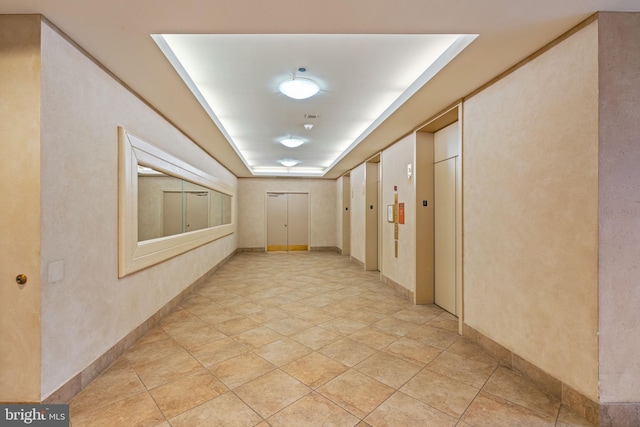 hallway with elevator and baseboards