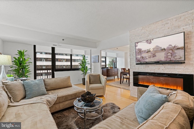 living area with a textured ceiling, a fireplace, and wood finished floors