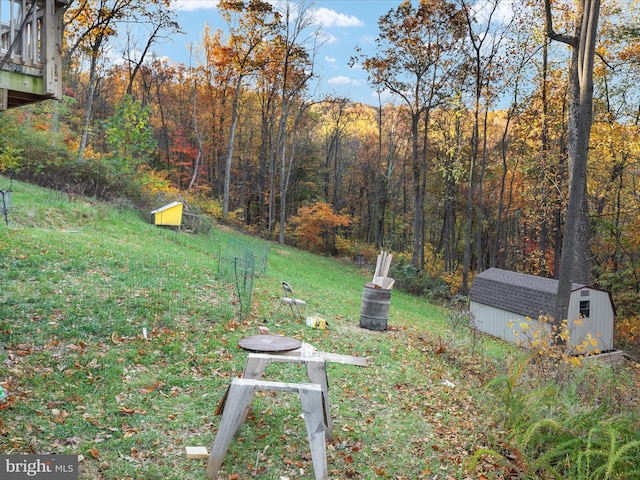 view of yard featuring an outdoor structure, a wooded view, and a shed