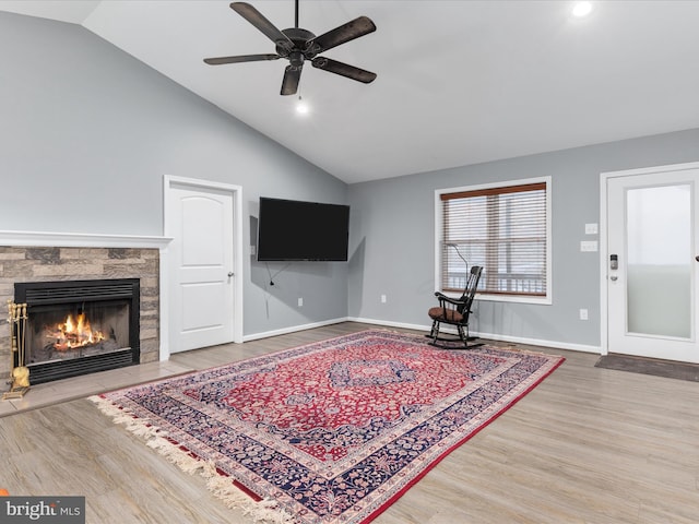 living room featuring baseboards, a ceiling fan, a tiled fireplace, wood finished floors, and high vaulted ceiling