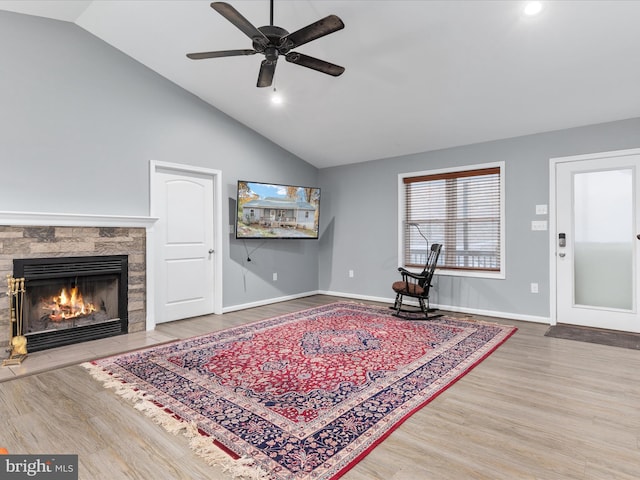 sitting room featuring baseboards, a ceiling fan, a tile fireplace, wood finished floors, and high vaulted ceiling