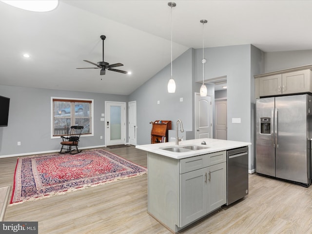 kitchen with stainless steel appliances, gray cabinets, open floor plan, a sink, and light wood-type flooring