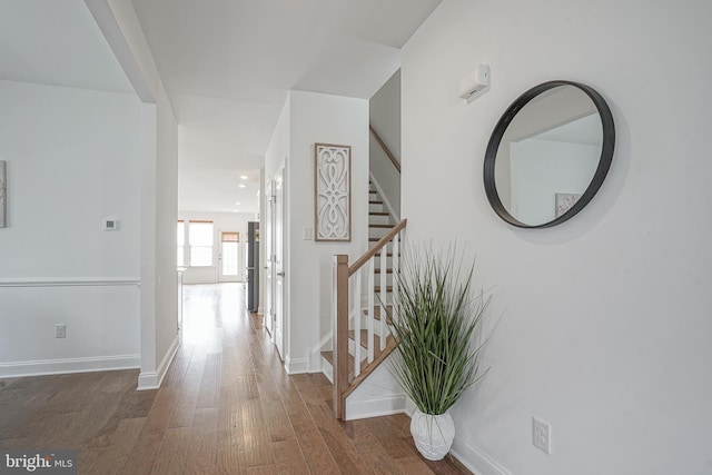 hall featuring baseboards, stairway, and wood finished floors