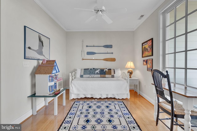 bedroom with ornamental molding, multiple windows, wood finished floors, and baseboards