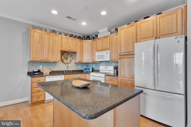 kitchen featuring a center island, visible vents, ornamental molding, light brown cabinets, and white appliances