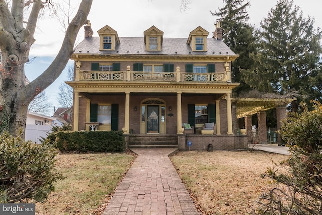 georgian-style home with brick siding, a porch, a high end roof, and a balcony