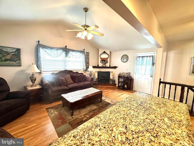 living room with a wealth of natural light, a fireplace, vaulted ceiling, and wood finished floors