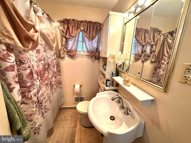 full bath with visible vents, toilet, a sink, tile patterned flooring, and baseboards