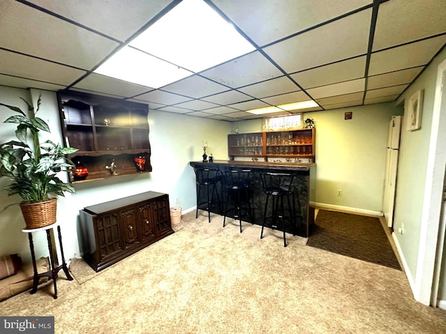 bar with baseboards, light colored carpet, a dry bar, and a drop ceiling