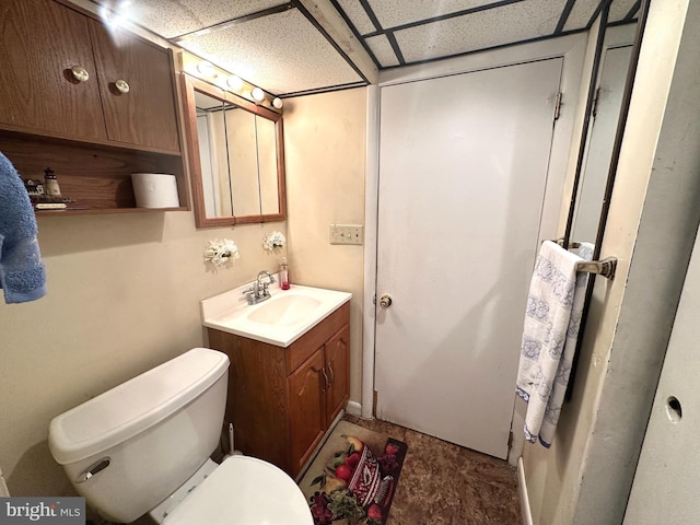 bathroom with toilet, a drop ceiling, and vanity