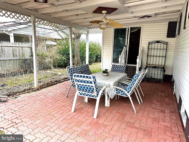 view of patio with fence, a ceiling fan, and outdoor dining space