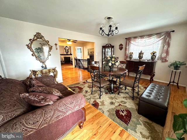 dining space with baseboards, plenty of natural light, an inviting chandelier, and wood finished floors