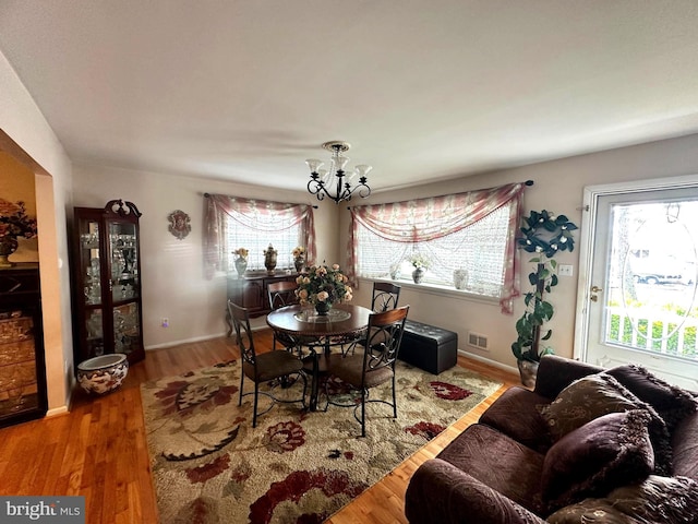 dining room featuring baseboards, a notable chandelier, visible vents, and wood finished floors