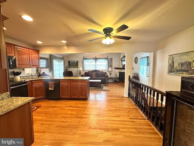 kitchen featuring brown cabinetry, open floor plan, a peninsula, and black appliances