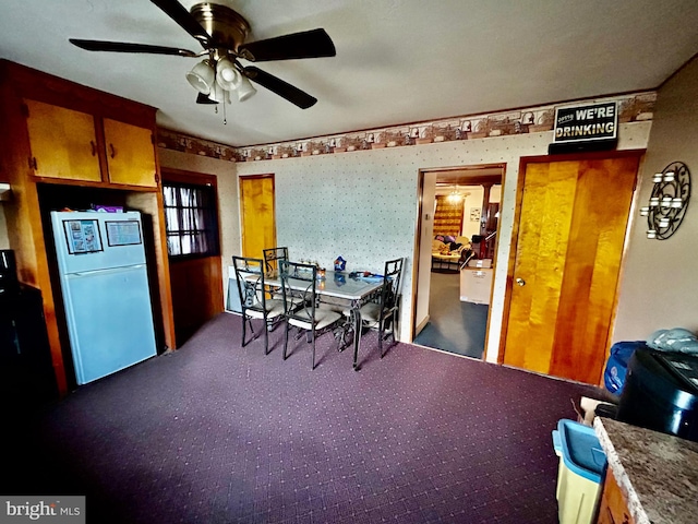 carpeted dining space featuring wallpapered walls and ceiling fan