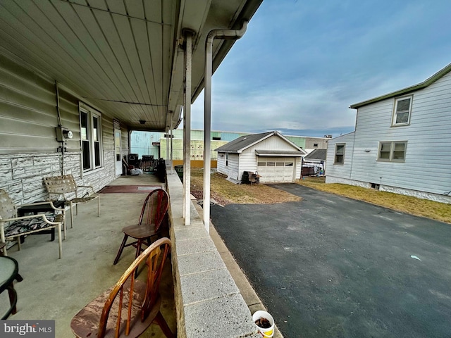 view of patio featuring a garage, driveway, and an outbuilding