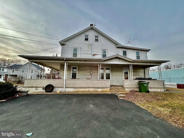 farmhouse with covered porch and aphalt driveway