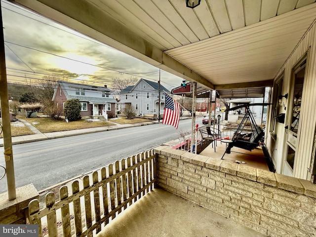 balcony at dusk featuring covered porch