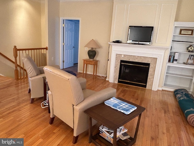 living room featuring built in shelves, light wood-style floors, and a high end fireplace